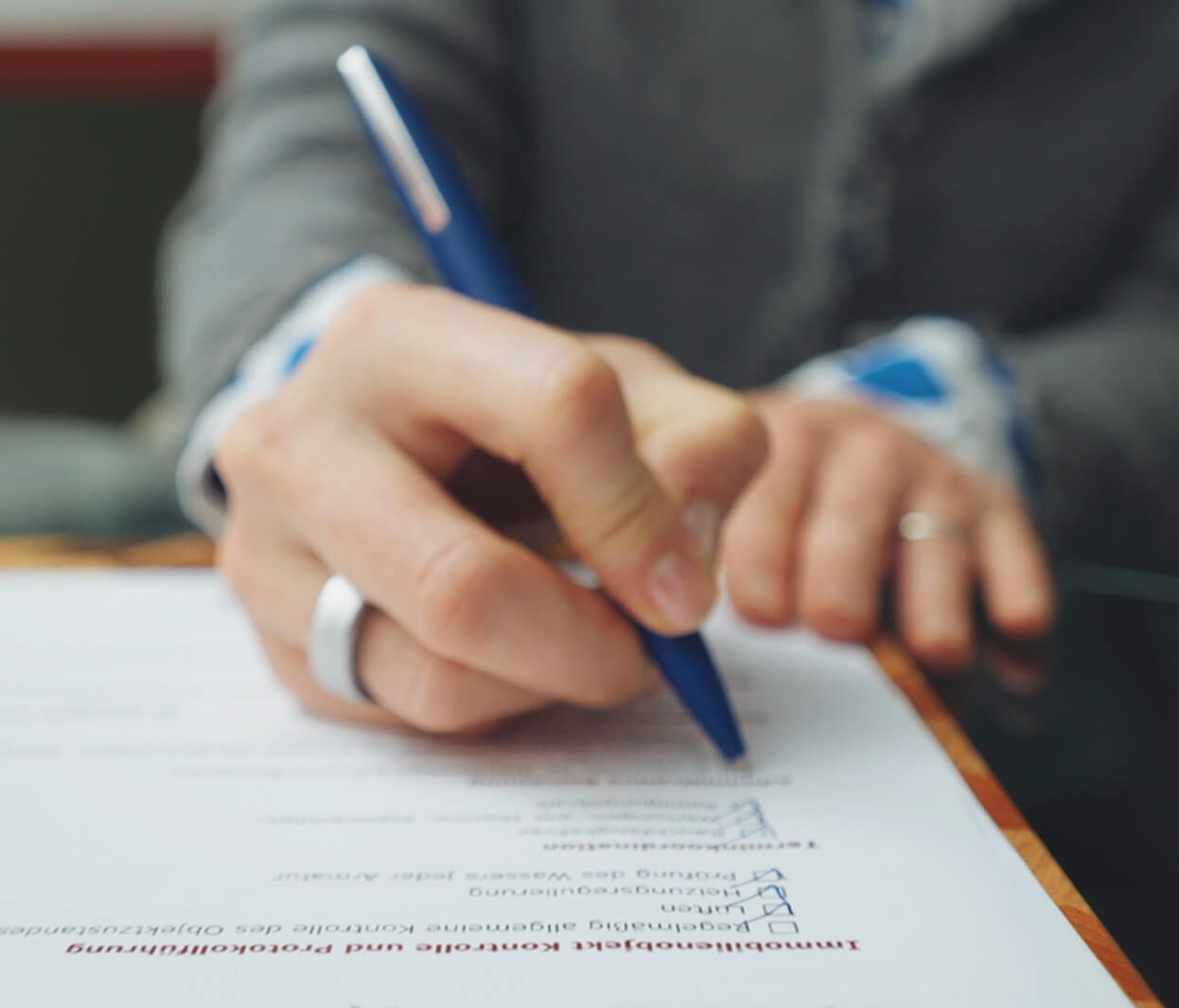 eine Frauenhand überarbeitet mit einem blauen Kugelschreibers eine Checkliste überarbeitet von Vienna Home Watchers - die professionelle Immobilienbetreuung in Wien